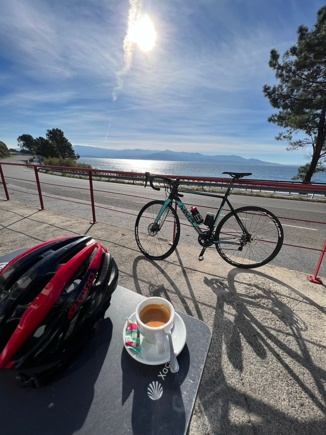 Bicicleta de carretera y casco junto a un café, con el mar de fondo